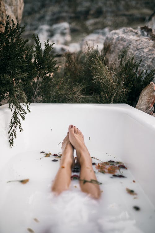 Free Bare Feet and Legs of a Person in Bathtub With Milky Water Stock Photo