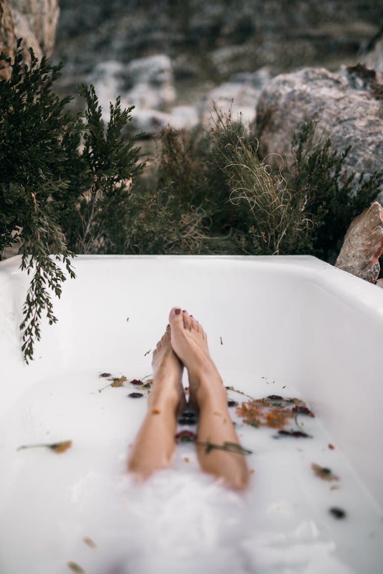 Bare Feet And Legs Of A Person In Bathtub With Milky Water