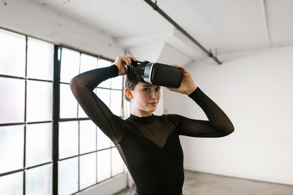 guide to virtual presentation skills - Woman using virtual reality headset in a minimalist indoor space, wearing black long sleeves.