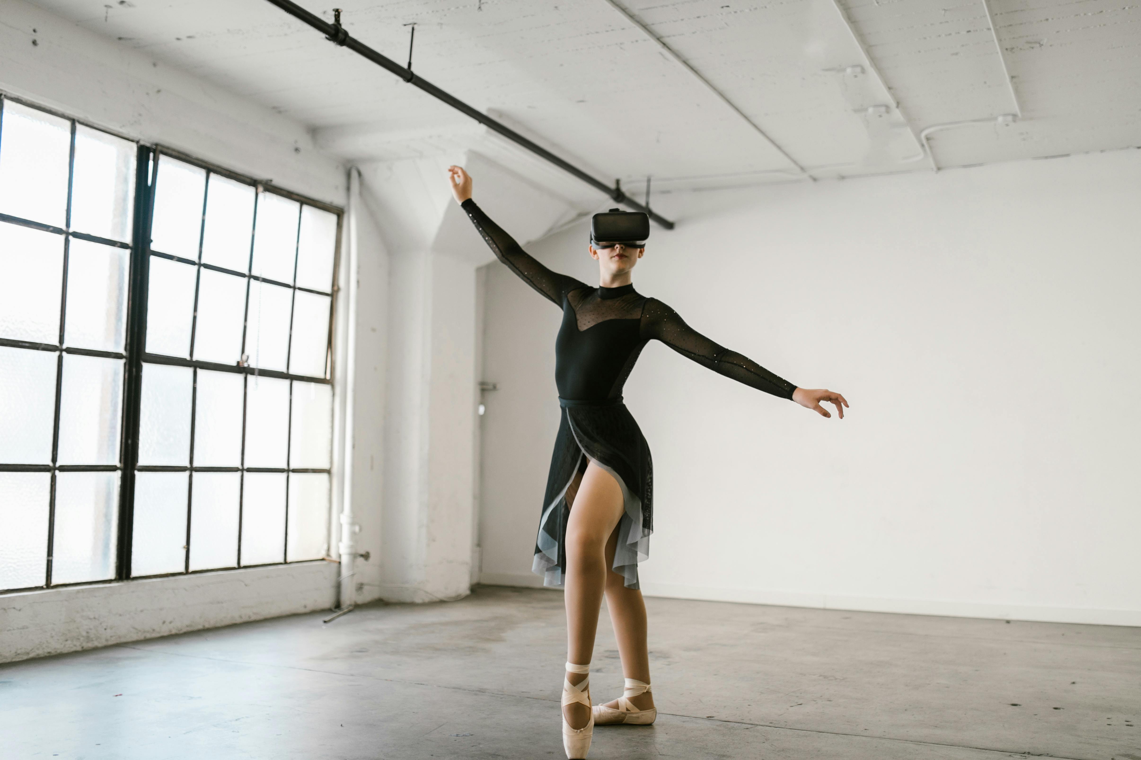 A dancer wearing a VR headset performs ballet in a spacious studio.