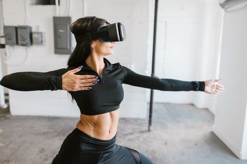 Free Woman engaging in fitness with VR headset indoors, exploring virtual workout technology. Stock Photo