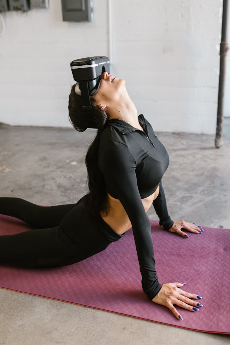 Woman Wearing Virtual Reality Goggles Bending Back On A Yoga Mat