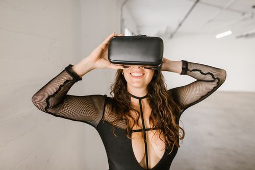 Free A woman smiles while using a virtual reality headset inside an empty room with a modern design. Stock Photo