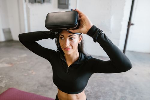 Free Smiling woman using virtual reality headset in a modern indoor setting. Stock Photo