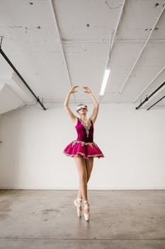 A ballerina wearing a virtual reality headset performs a dance pose in a modern studio setting.