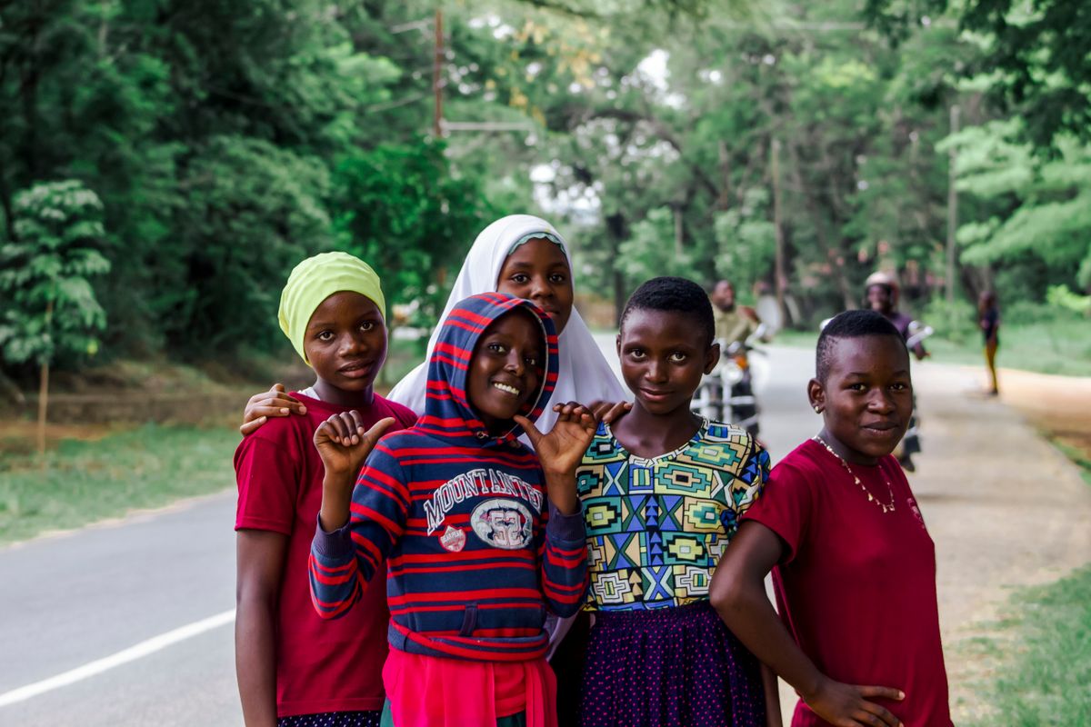 A cheerful group of children smiling on a peaceful road surrounded by greenery