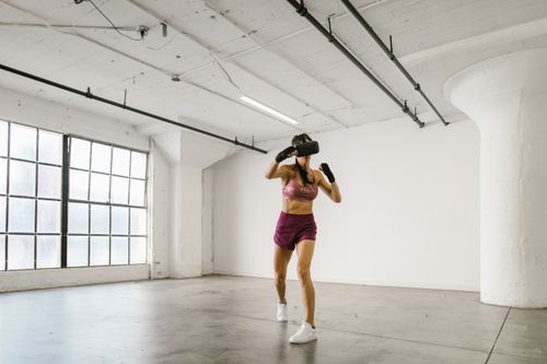 Free Adult woman using VR headset for fitness exercise in a modern indoor gym environment. Stock Photo