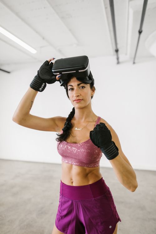 Free Athletic woman in a gym wearing a VR headset and workout gear. Perfect for modern lifestyle and fitness concepts. Stock Photo