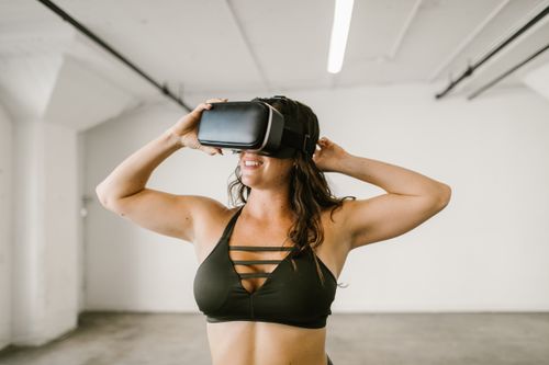 Free Adult woman in workout attire exploring virtual reality indoors. Stock Photo