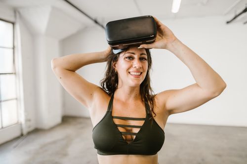Free Smiling woman in a modern space trying a virtual reality headset indoors. Stock Photo