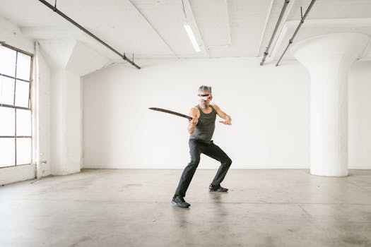 Adult man practicing martial arts with a blade and VR headset in a spacious, bright indoor setting.
