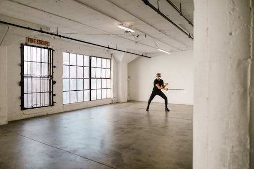 A man in an empty room practicing martial arts with a VR headset, showcasing modern training techniques.