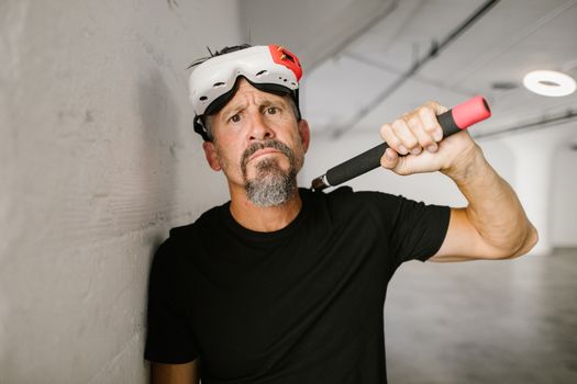 A bearded man wearing a VR headset poses indoors holding nunchaku.