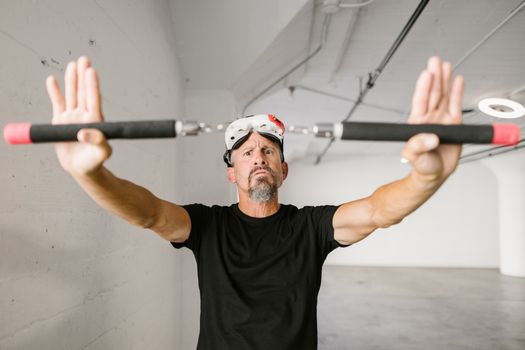 Man in black shirt holds nunchucks with VR goggles in modern indoor space.