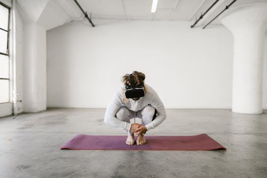 A woman in sportswear using a virtual reality headset while doing yoga indoors on a mat.