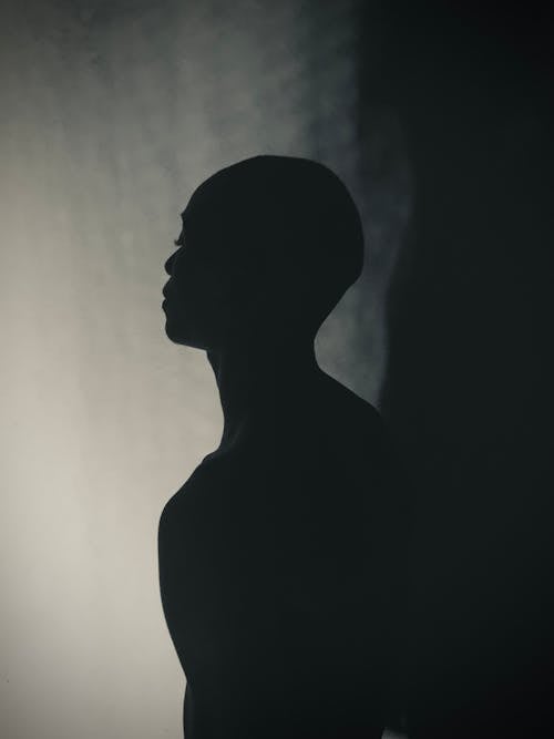 A Silhouette of a Person Standing Beside the Wall