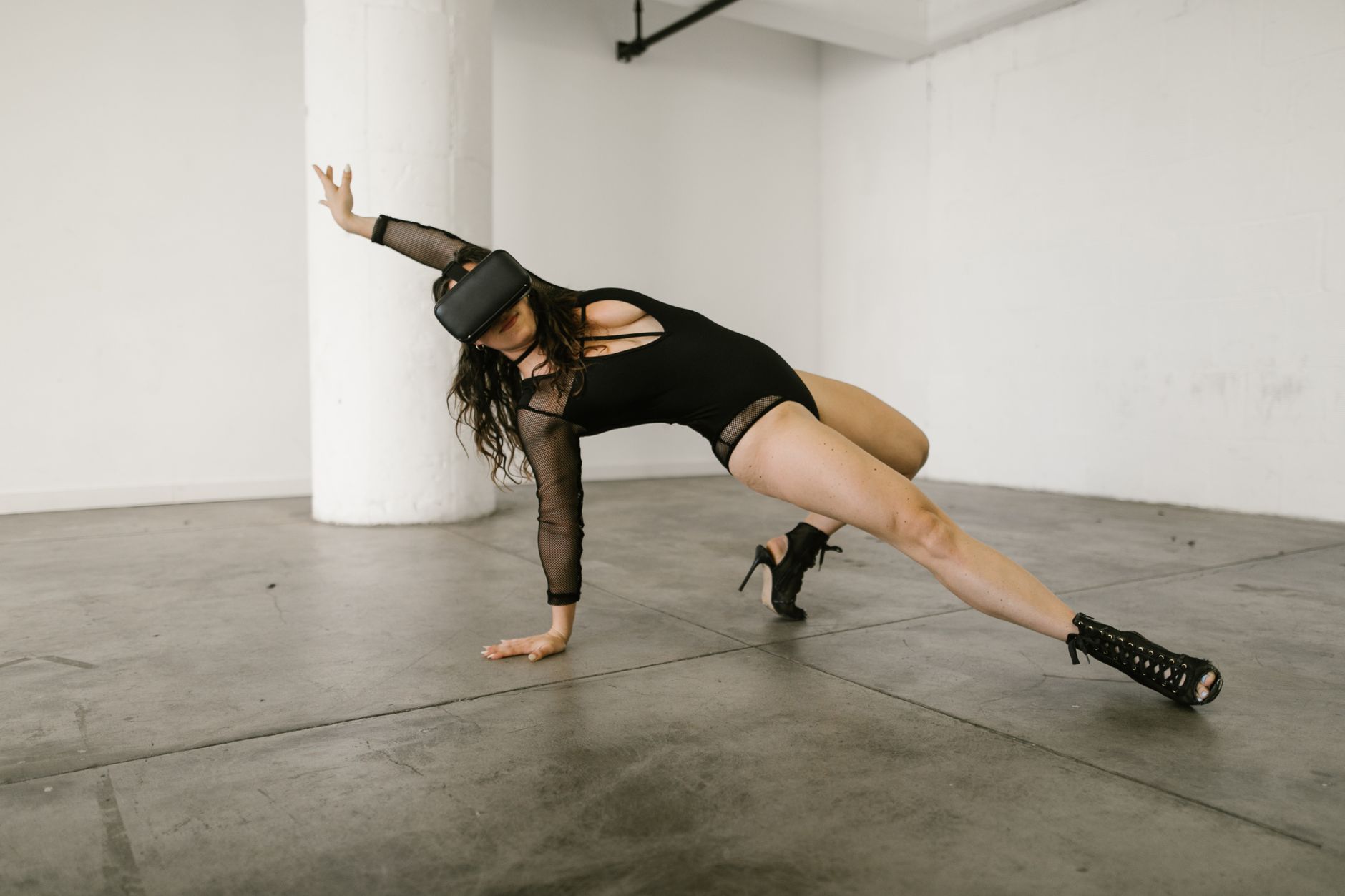 A woman dancer performs stylish moves wearing a virtual reality headset indoors, showcasing modern technology in dance.