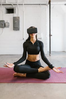 Woman in black activewear meditating in a lotus position with virtual reality headset in an industrial studio.