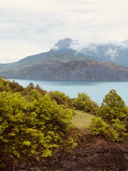 Tranquil landscape of Lake Serre-Ponçon with lush greenery in Rousset, France.