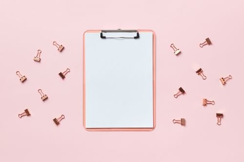 Free A flatlay of a clipboard with binder clips on a pastel pink background, showcasing minimalism. Stock Photo