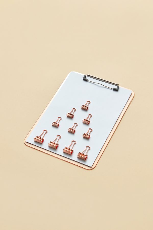 Clipboard with rose gold binder clips on a warm surface, by DS stories on Pexels