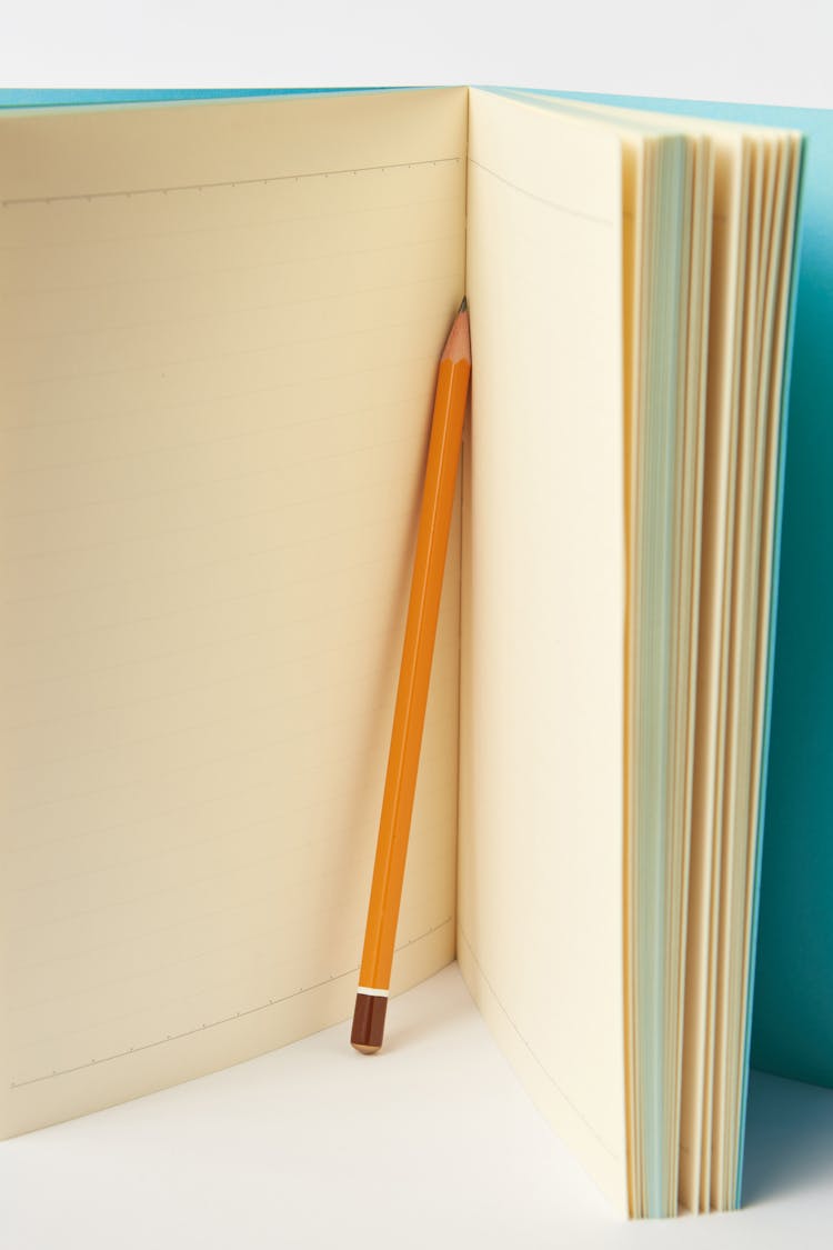 A Yellow Pencil In Between The Pages Of A Notebook