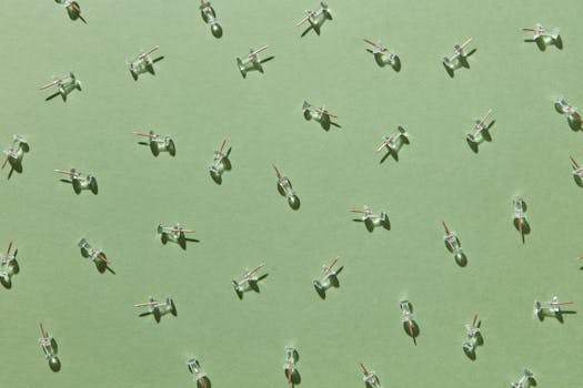 Transparent push pins arranged in a pattern on green paper, creating a minimalistic and modern effect.