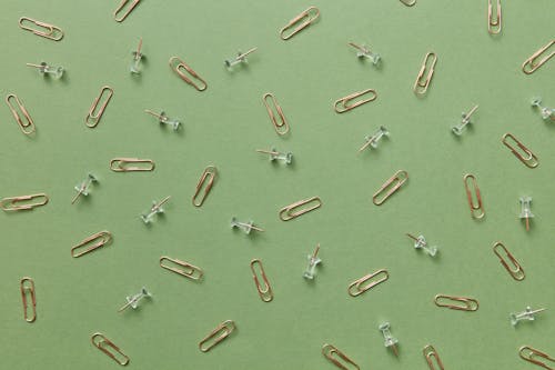 Paper Clips and Pins on Green Surface