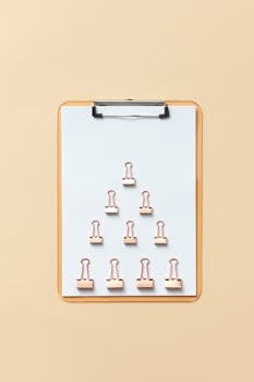 Flat lay of binder clips arranged on a clipboard against a neutral background.