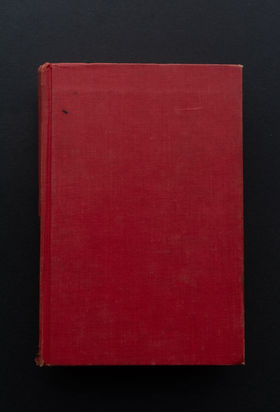 A plain crimson cloth-bound hardcover on a dark ground — Namukolo Siyumbwa on Pexels
