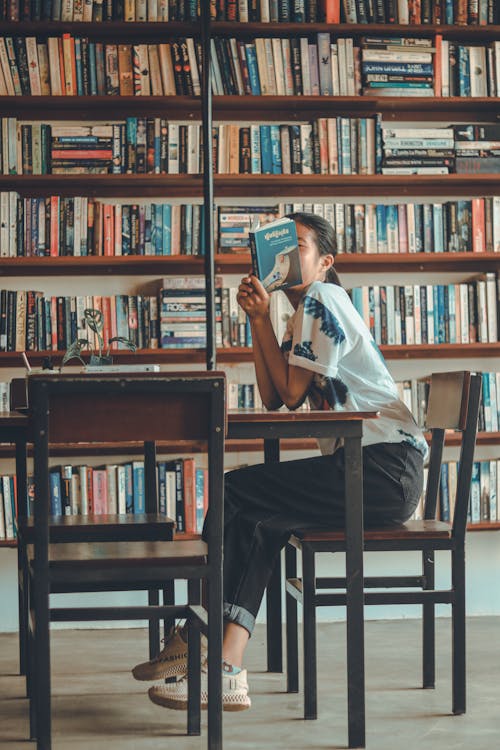 Woman Holding a Book While Sitting on Chair