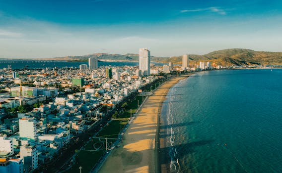 Stunning aerial view of a coastal cityscape with a wide beach, skyscrapers, and sea.