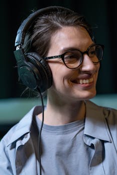 Portrait of a happy woman wearing headphones and eyeglasses indoors.