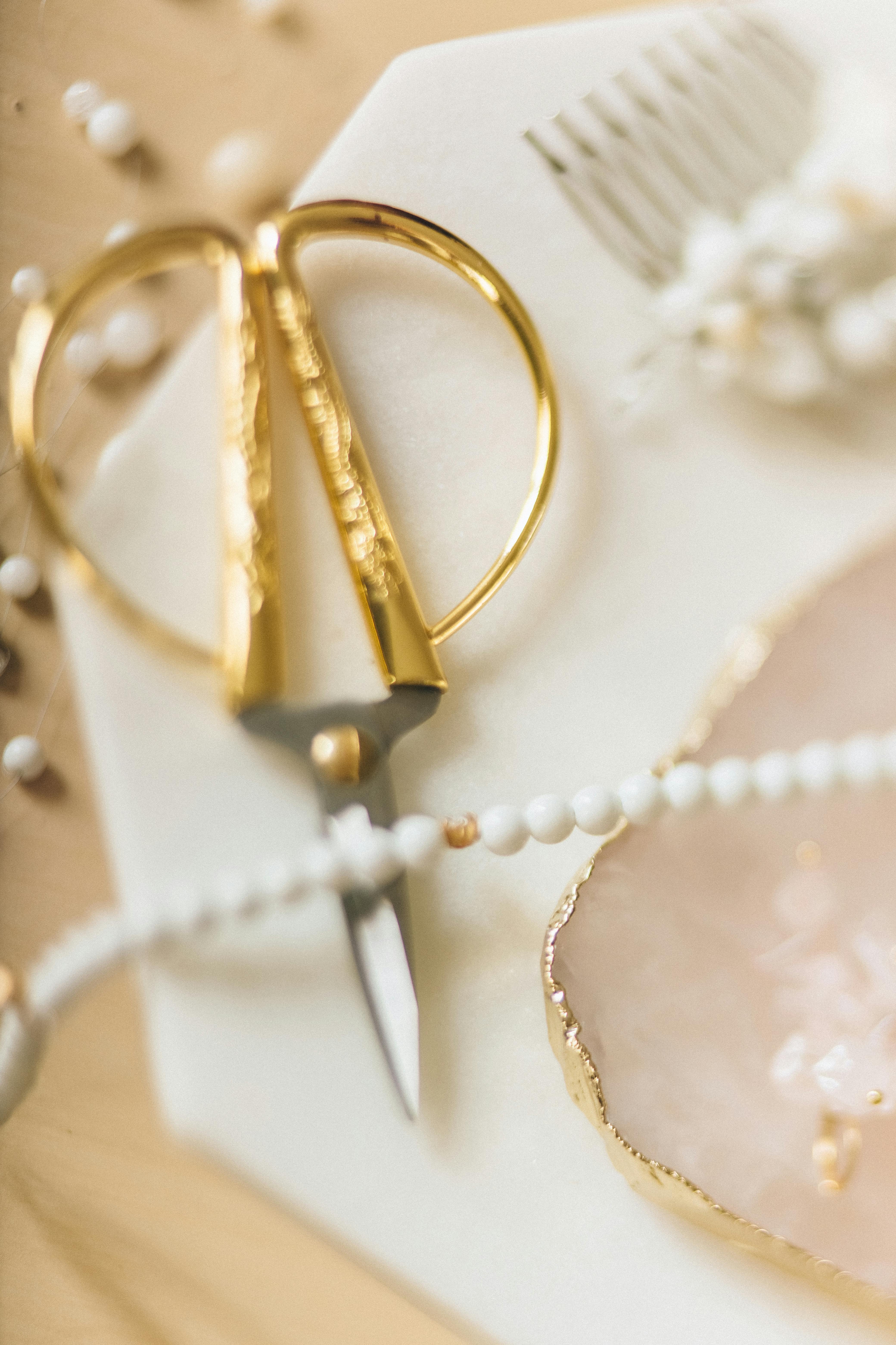 a string of whites beads on a pair of scissors with gold handles