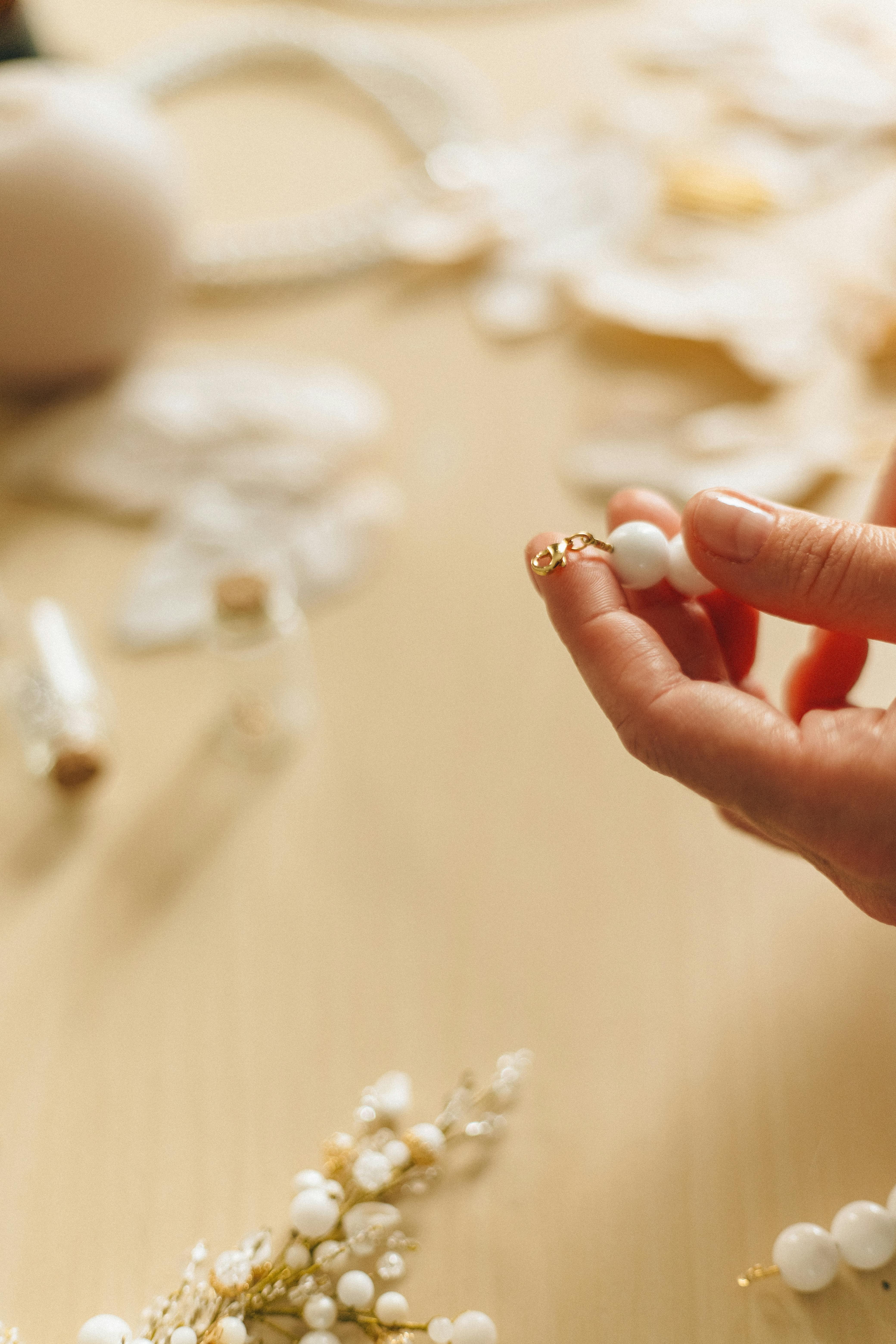 person holding white pearl stud earrings