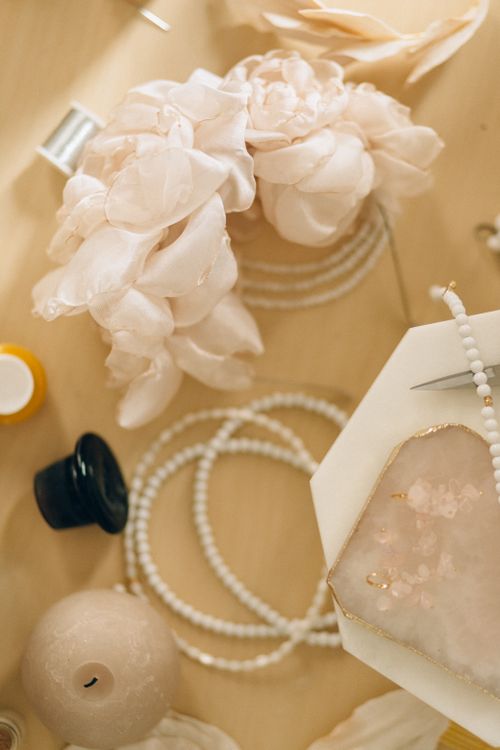 Free A beautifully arranged flat lay of beaded jewelry and delicate floral accessories on a wooden surface. Stock Photo