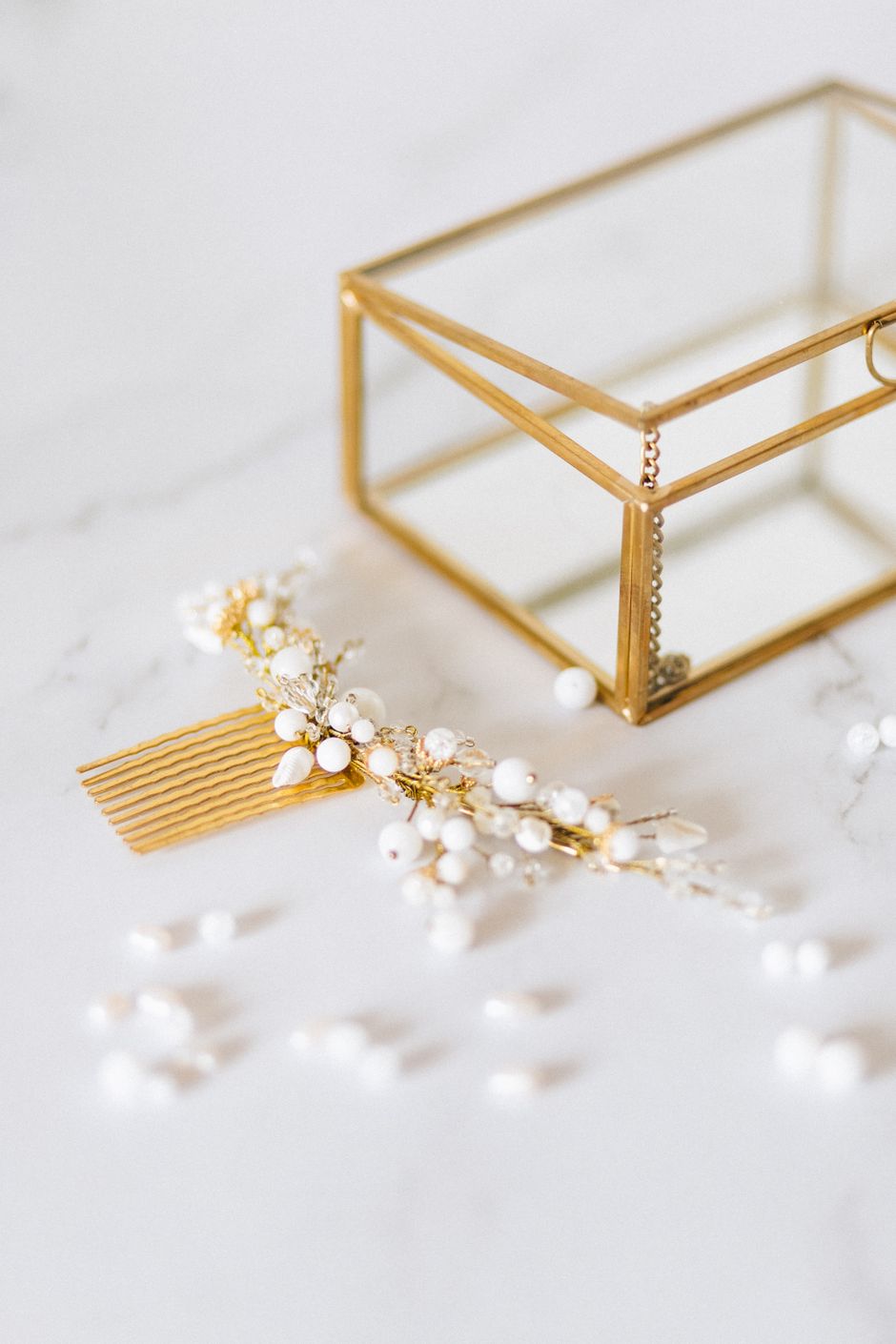 Gold and pearl jewelry beside a glass jewelry box