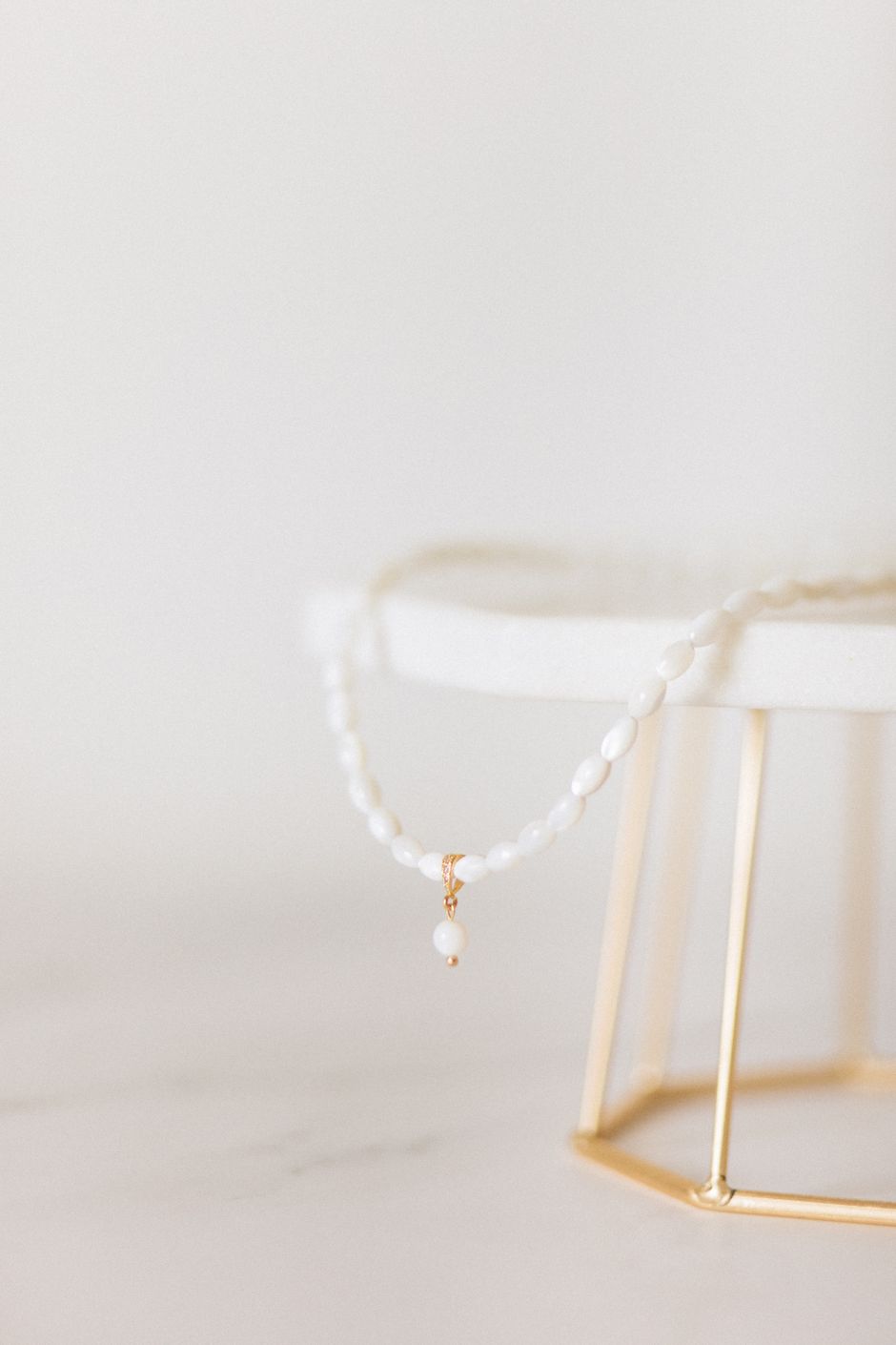 A delicate white beaded necklace displayed on a jewelry stand