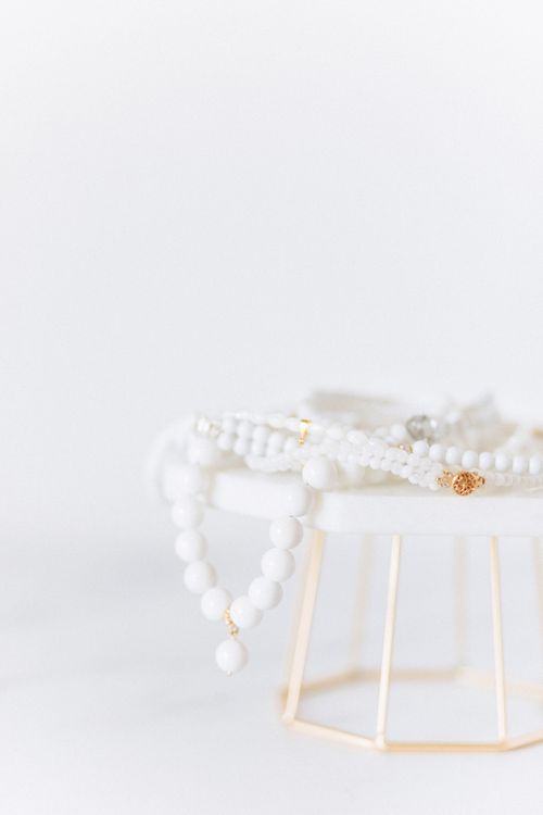 Free Close-up of elegant white beaded jewelry resting on a minimalist stand with a soft focus background. Stock Photo