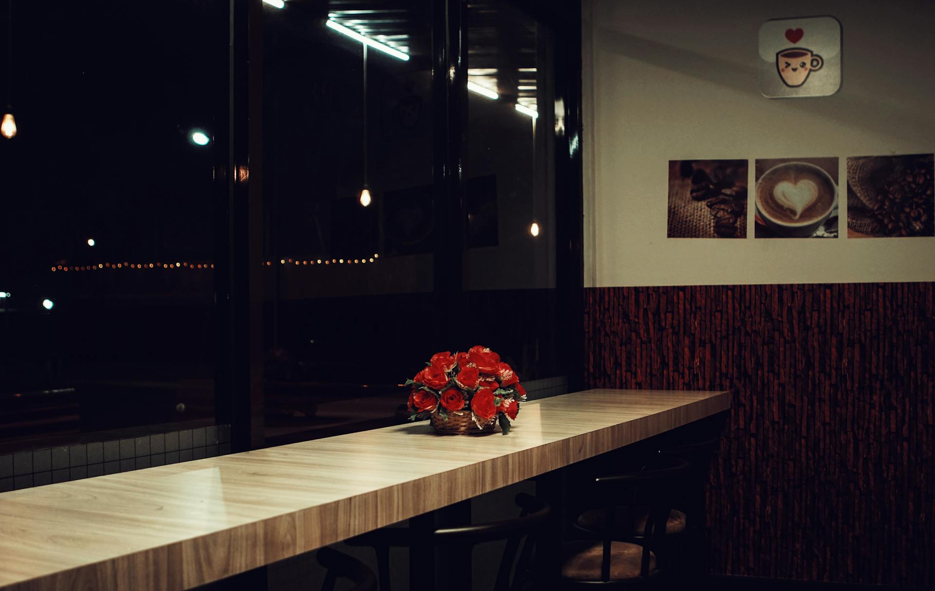 Contemporary coffee shop interior featuring minimalist design with red flowers and ambient lighting.