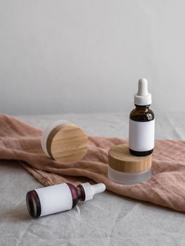 Elegant arrangement of cosmetic bottles with dropper lids on a soft textile surface.