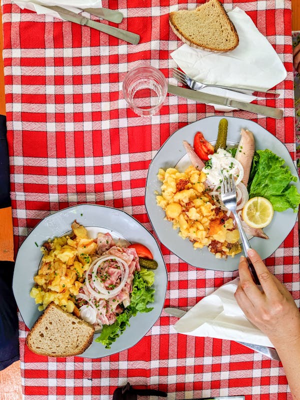 Person Holding Stainless Steel Fork and Knife on White Ceramic Plate
