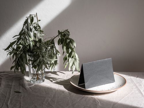 Free Elegant minimalist composition featuring a blank card and ceramic plate adorned by leaves in natural light. Stock Photo