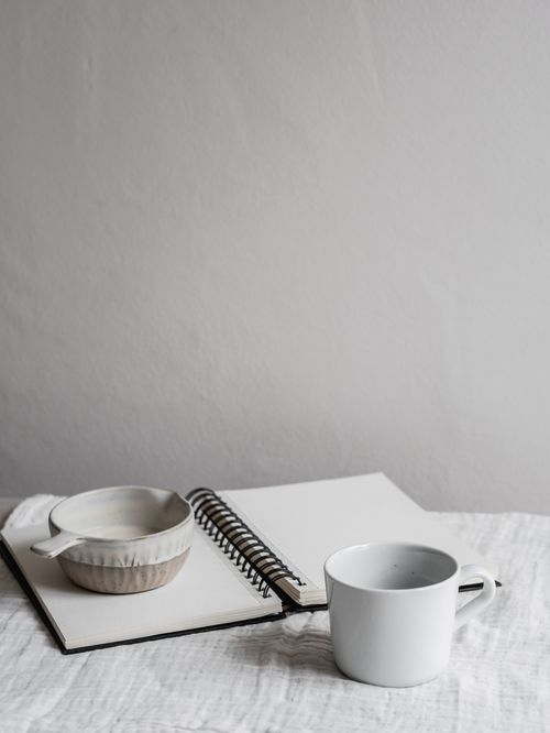 Free Elegant minimalist workspace featuring a cup and open notebook, perfect for creativity and focus. Stock Photo