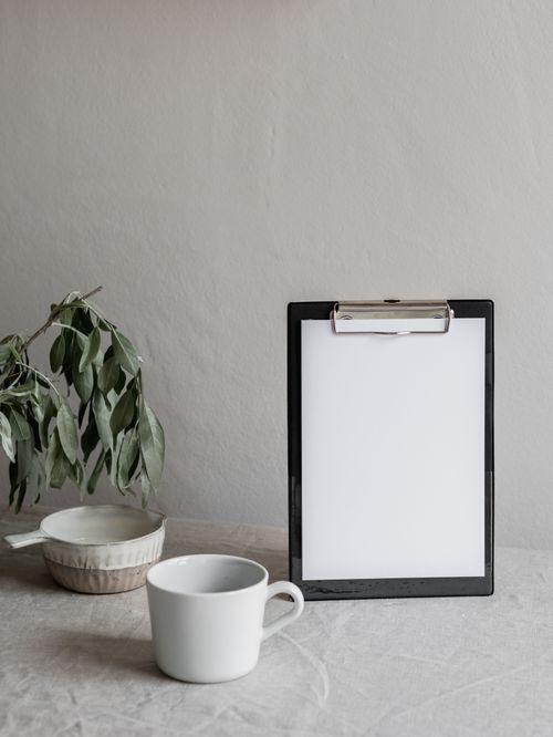 Free Elegant minimalist workspace with clipboard, ceramic mug, and green plant. Stock Photo