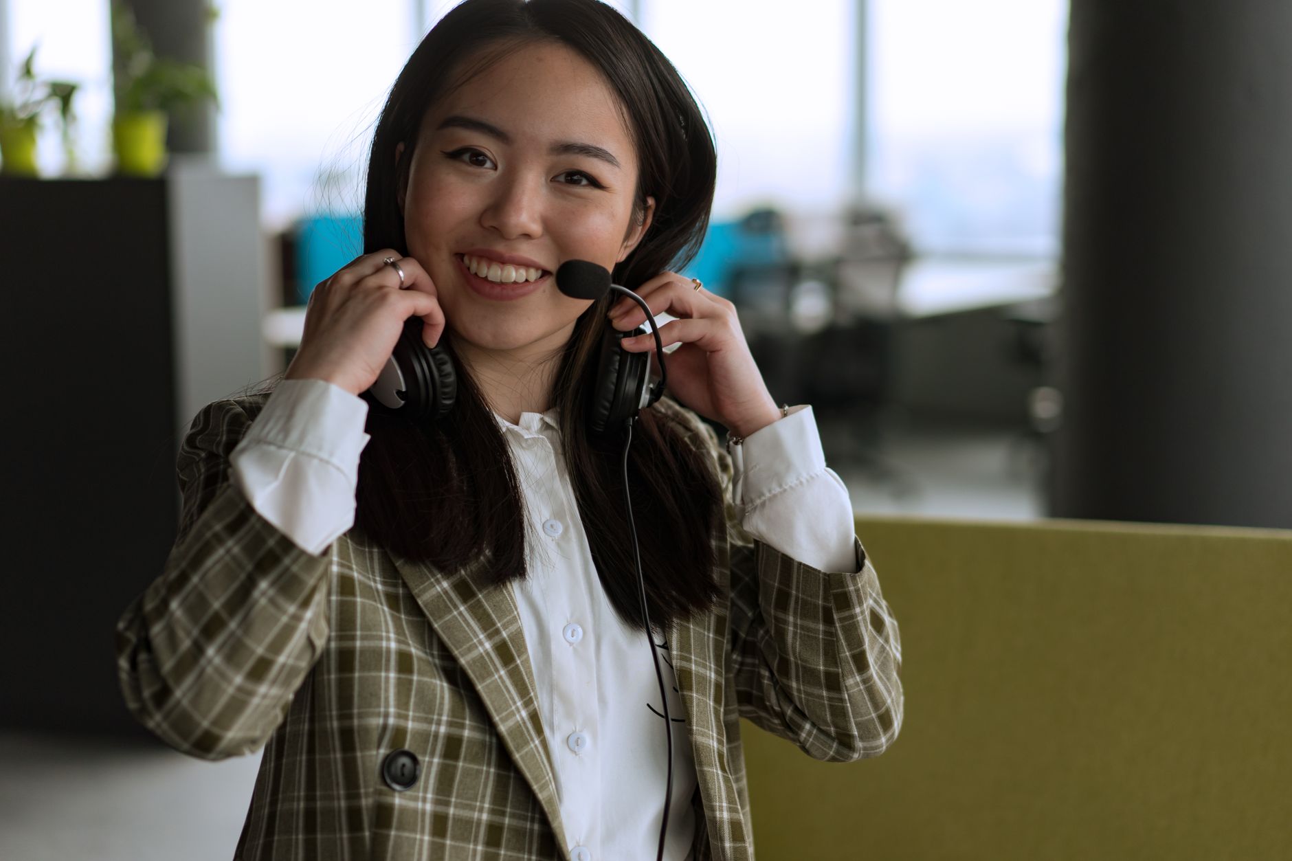 Confident woman using a headset and smiling in a modern office setting.