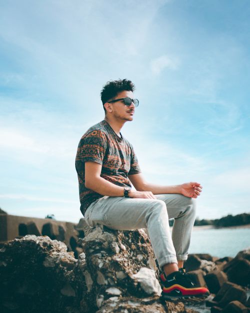Free Young man in casual wear enjoying a sunny day by the sea, exuding style and relaxation. Stock Photo