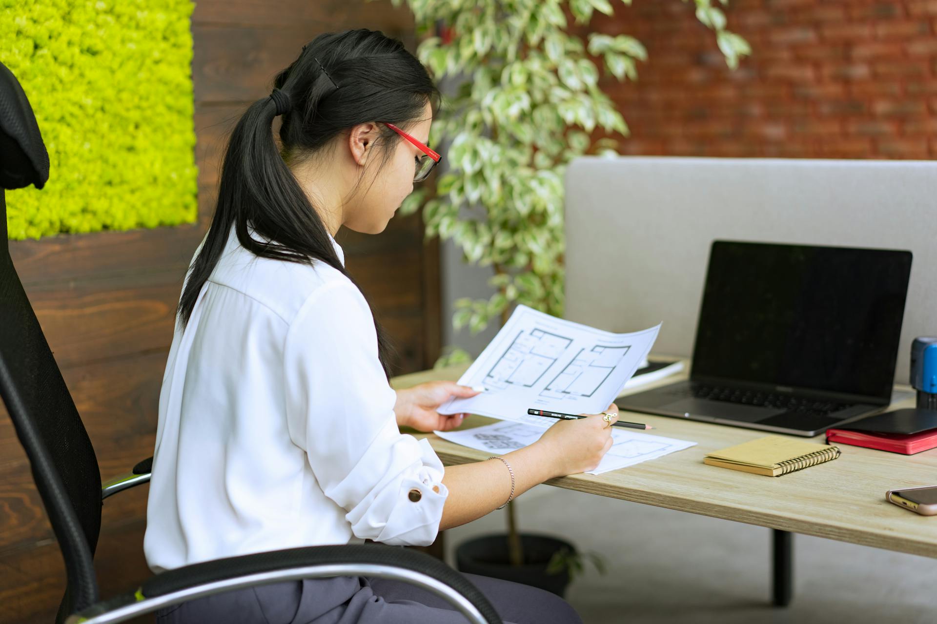 Professional woman analyzing architectural plans at her office desk.