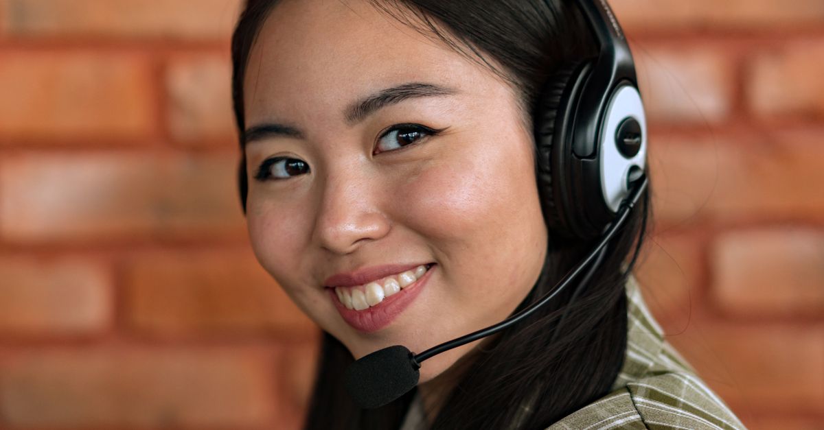 Close-up of a young Asian woman wearing headphones and smiling, indoors.