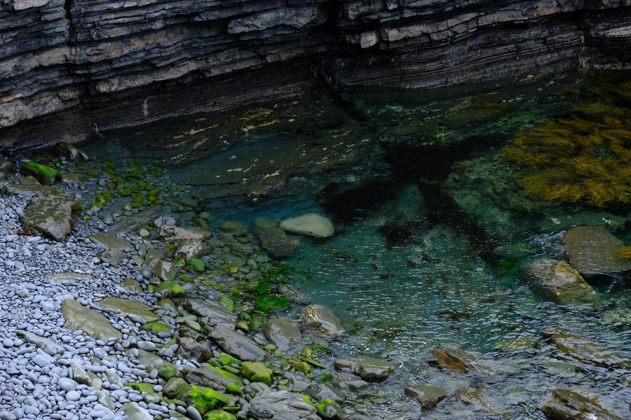 A rocky pool in a cove in County Clare, Ireland with clear water and stone formations